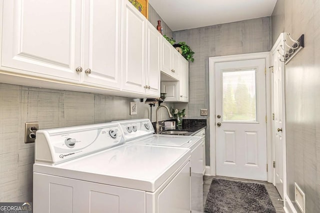 clothes washing area featuring cabinet space, separate washer and dryer, and a sink