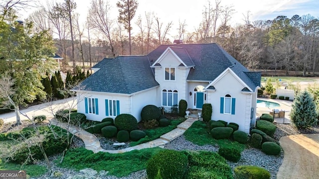 view of front of house with a shingled roof, a chimney, and stucco siding