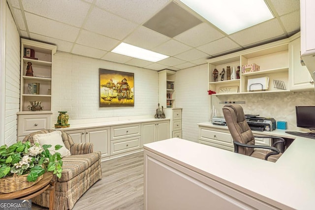 home office with a drop ceiling and light wood-type flooring