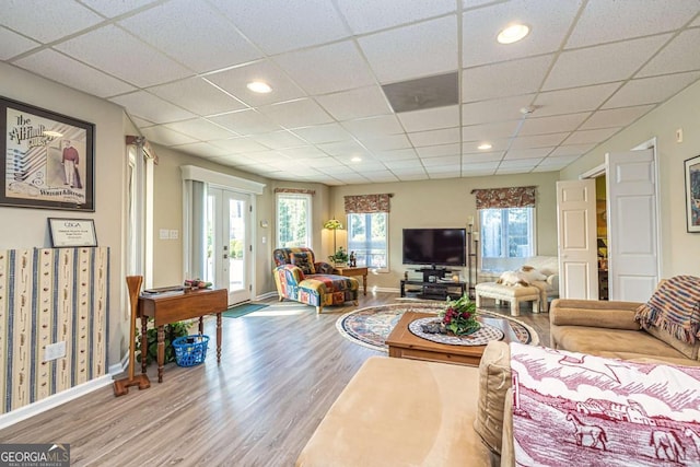 living room with french doors, a drop ceiling, wood finished floors, and baseboards