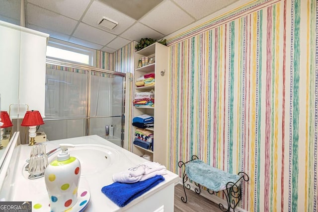 bathroom featuring a paneled ceiling, wood finished floors, and vanity