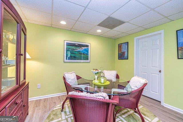 dining room with a drop ceiling, baseboards, and wood finished floors