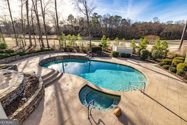 view of swimming pool with fence, a fenced in pool, and an in ground hot tub