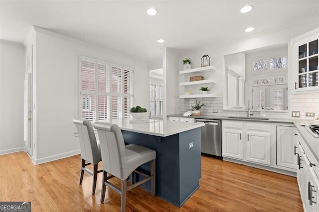 kitchen featuring a center island, open shelves, white cabinets, a sink, and dishwasher