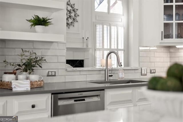 kitchen featuring dishwasher, a sink, glass insert cabinets, and white cabinetry