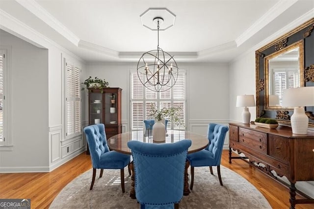 dining area featuring a chandelier, ornamental molding, and a raised ceiling