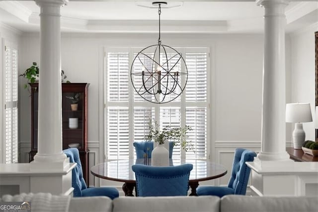 dining area with crown molding, a decorative wall, wainscoting, and ornate columns