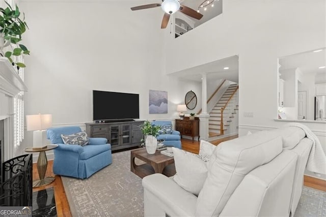 living area with ceiling fan, light wood-style flooring, stairway, and a high end fireplace