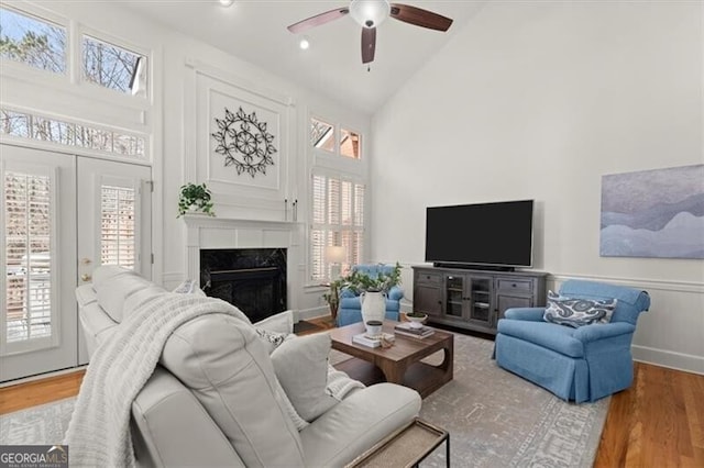 living room with high vaulted ceiling, a high end fireplace, and wood finished floors