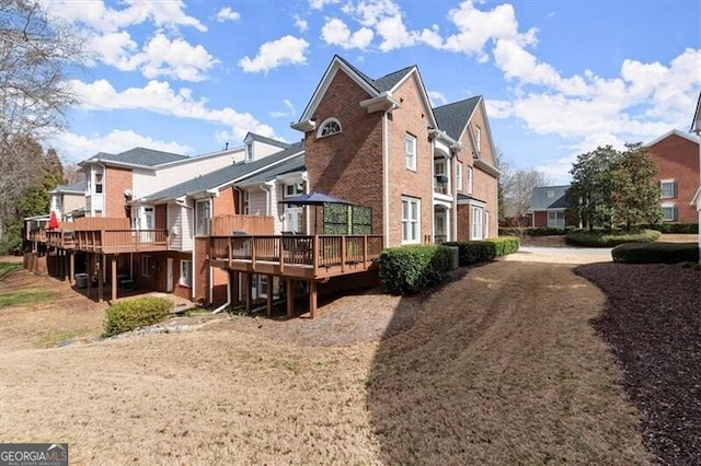 view of side of home with a deck, brick siding, and a residential view