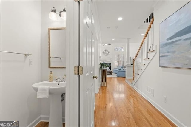 hallway featuring light wood finished floors, stairs, baseboards, and recessed lighting