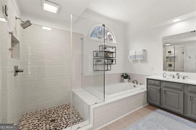 bathroom with a garden tub, a tile shower, vanity, and tile patterned floors