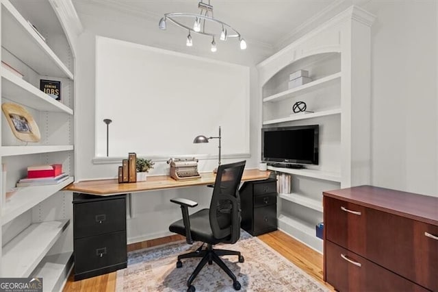 office space featuring light wood-style floors, crown molding, and built in desk