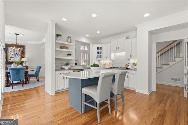 kitchen featuring a center island, light countertops, hanging light fixtures, glass insert cabinets, and white cabinetry