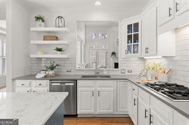 kitchen with stainless steel appliances, white cabinetry, a sink, and glass insert cabinets