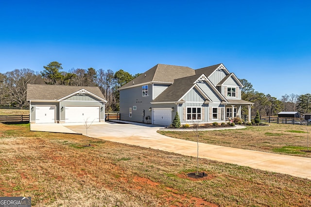 view of front of house with board and batten siding, fence, a front yard, a garage, and driveway