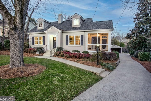 new england style home with a front yard, roof with shingles, an outdoor structure, and a chimney