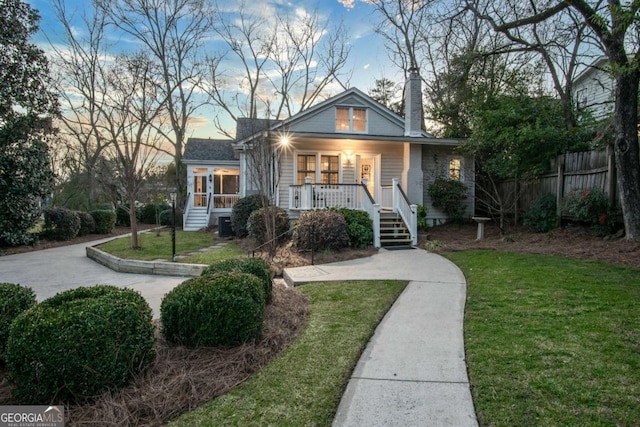 bungalow-style house featuring a sunroom, fence, a chimney, and a front lawn