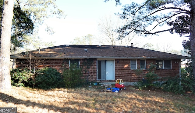 rear view of house featuring a yard and brick siding