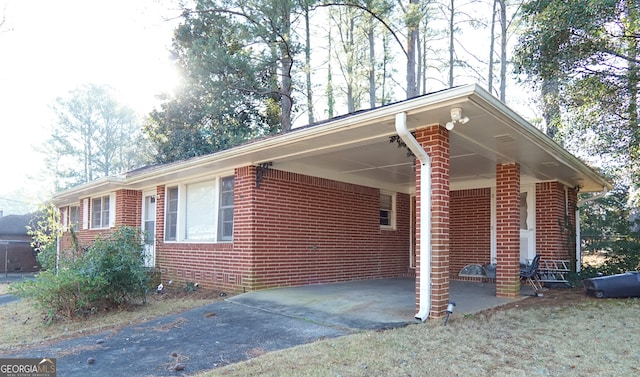 view of side of property with driveway, an attached carport, and brick siding