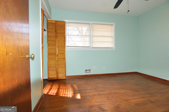 unfurnished bedroom with ceiling fan, baseboards, visible vents, and dark wood finished floors