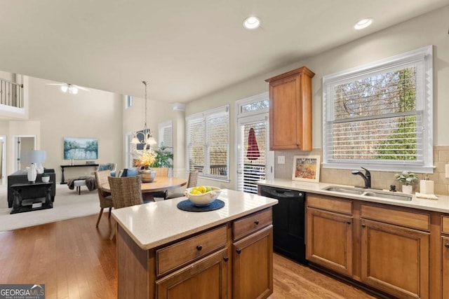 kitchen featuring light countertops, a sink, decorative light fixtures, and dishwasher