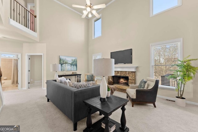 carpeted living area featuring visible vents, ceiling fan, a stone fireplace, and baseboards