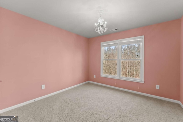 empty room featuring a chandelier, carpet, visible vents, and baseboards