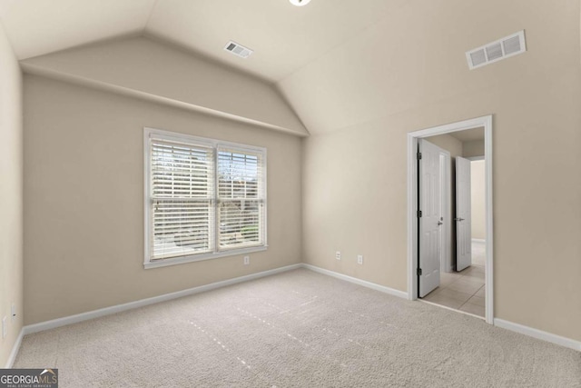 unfurnished bedroom with lofted ceiling, baseboards, visible vents, and light colored carpet