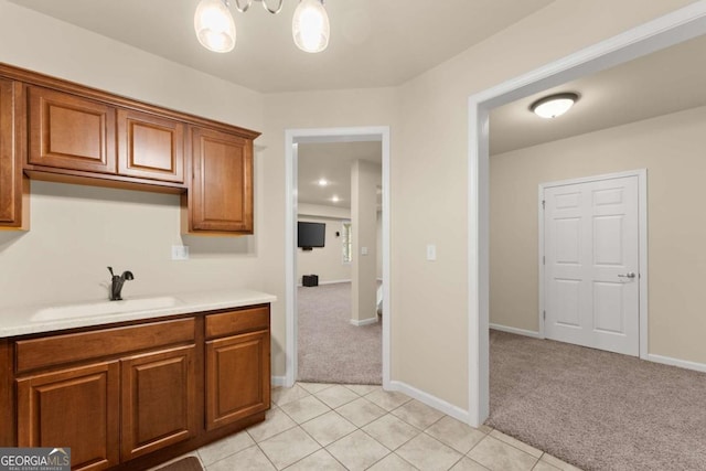 kitchen with light carpet, light countertops, brown cabinetry, and a sink