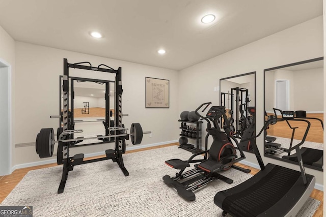 workout room featuring baseboards, light wood finished floors, and recessed lighting