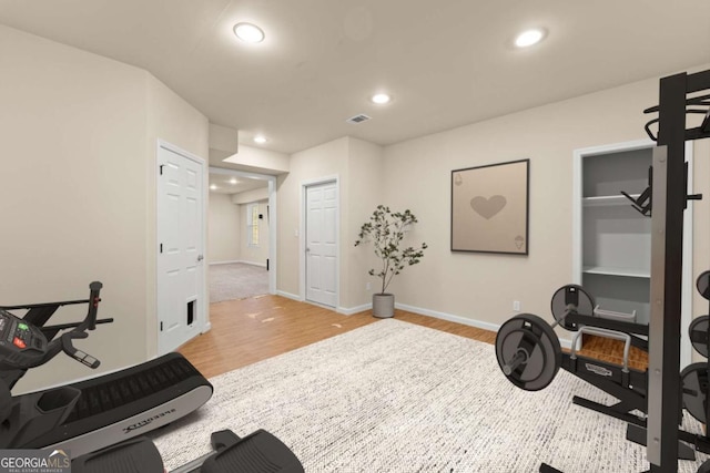 exercise room with light wood-type flooring, recessed lighting, visible vents, and baseboards