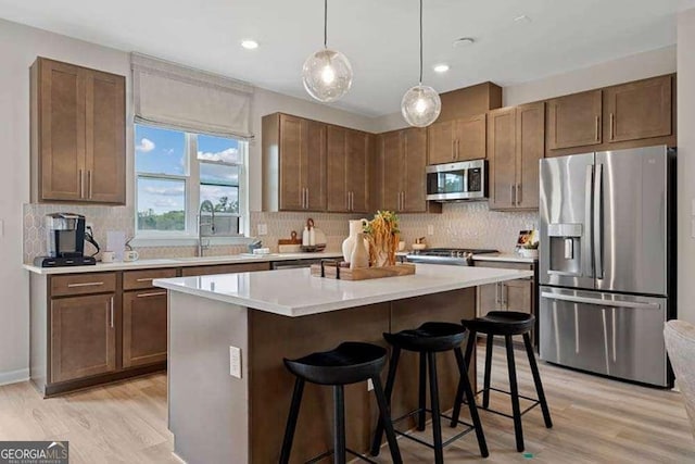 kitchen featuring a center island, a breakfast bar area, stainless steel appliances, light countertops, and a sink