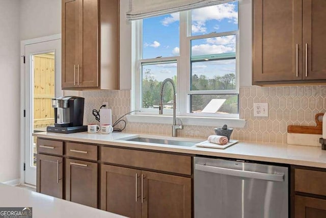 kitchen with dishwasher, light countertops, a sink, and brown cabinets