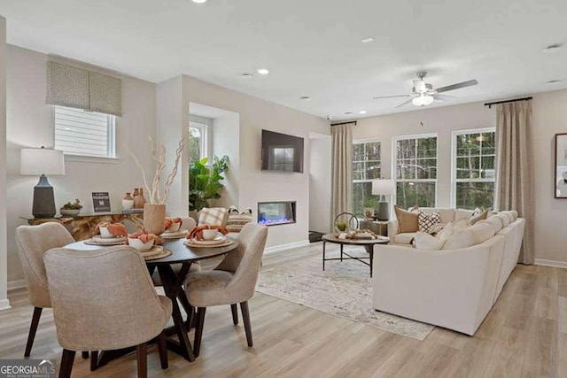 interior space featuring recessed lighting, light wood-type flooring, a glass covered fireplace, and baseboards