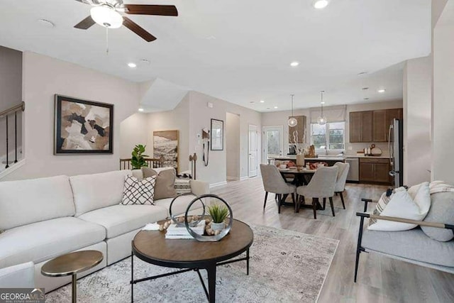 living area with light wood-style floors, ceiling fan, and recessed lighting