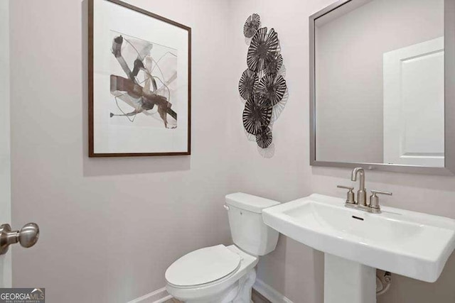 bathroom with a sink, toilet, and baseboards