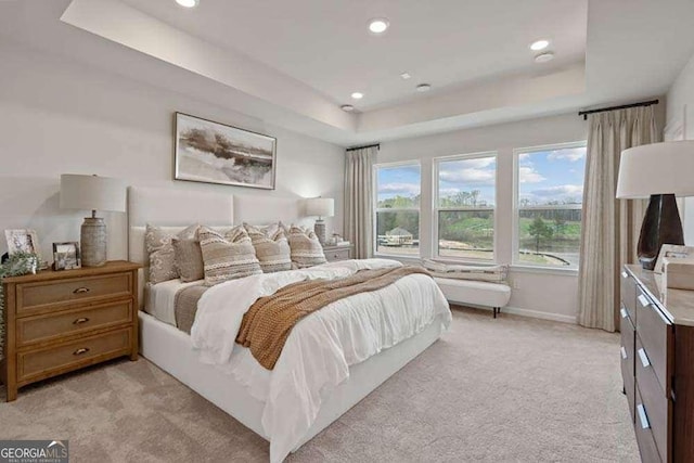 bedroom with recessed lighting, a tray ceiling, baseboards, and light colored carpet