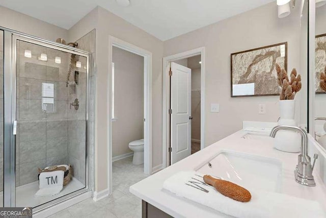 bathroom featuring toilet, a shower stall, double vanity, and a sink