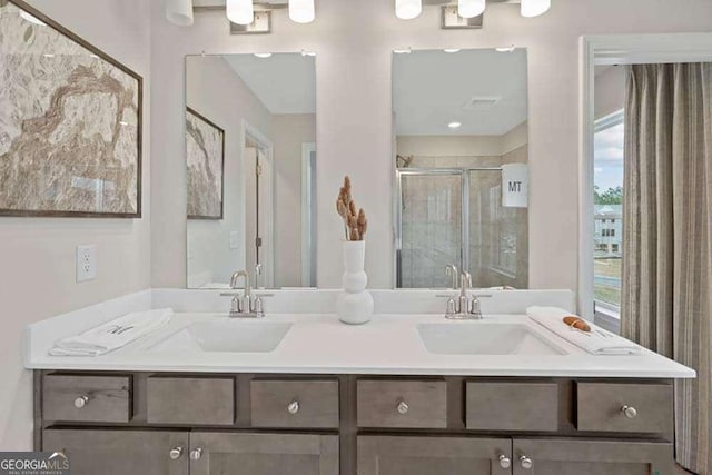 full bath featuring double vanity, a stall shower, and a sink