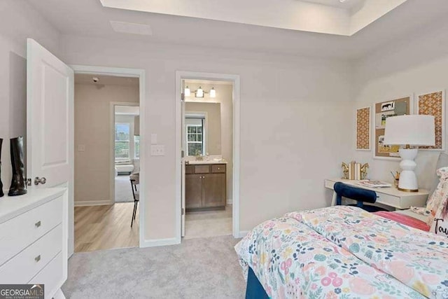 bedroom featuring light carpet, ensuite bath, and baseboards