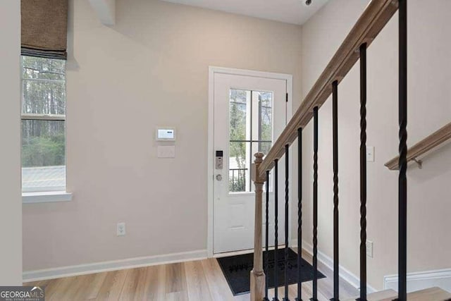 entryway with light wood-style floors, baseboards, and stairs