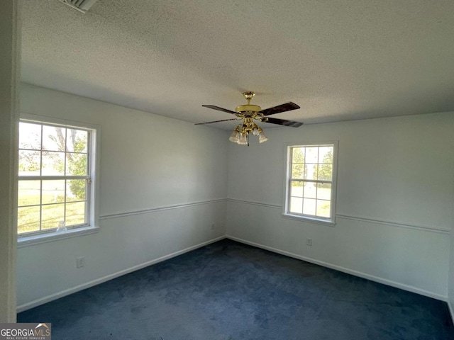 spare room featuring ceiling fan, baseboards, dark colored carpet, and a textured ceiling