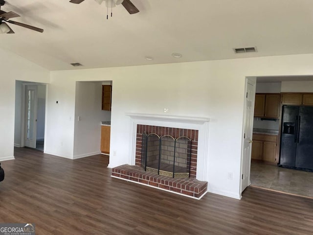 unfurnished living room with dark wood-type flooring, a brick fireplace, and visible vents