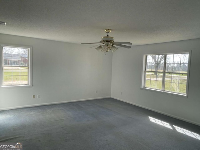 spare room featuring a textured ceiling, ceiling fan, visible vents, baseboards, and dark carpet