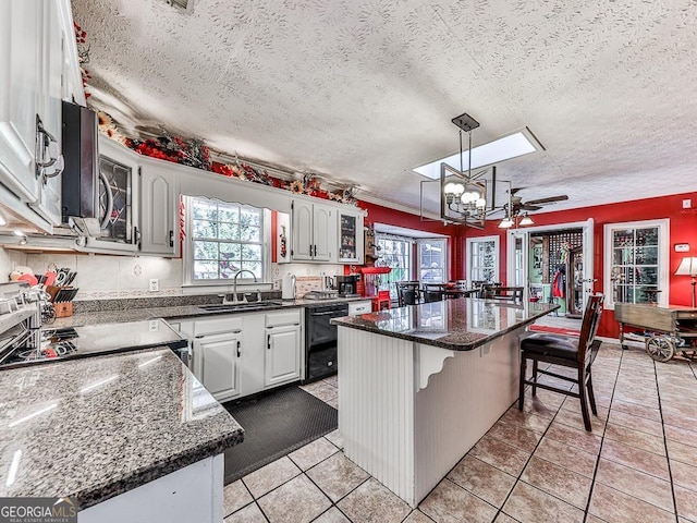 kitchen featuring black dishwasher, white cabinets, a sink, and a center island