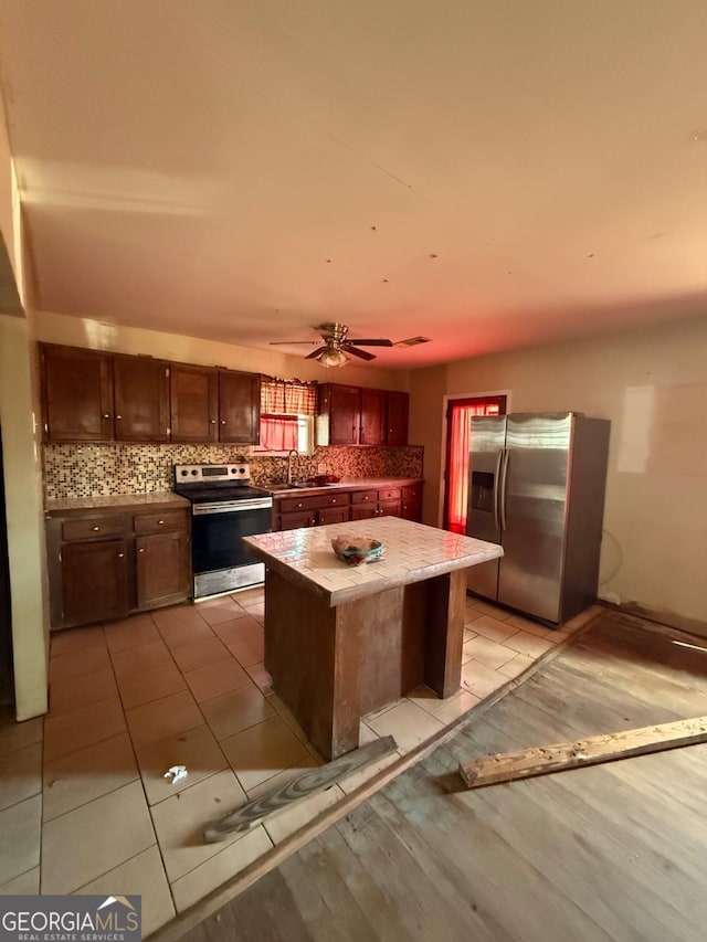 kitchen featuring appliances with stainless steel finishes, decorative backsplash, light wood-style flooring, and a center island