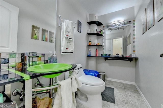 bathroom featuring backsplash, tile patterned flooring, toilet, and baseboards