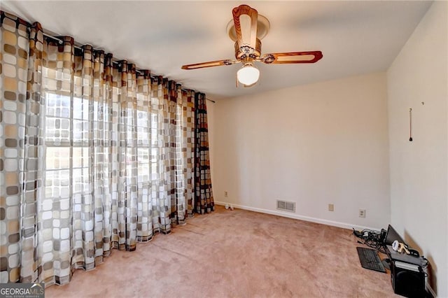 empty room with carpet, visible vents, ceiling fan, and baseboards