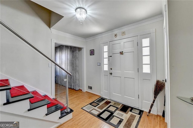 entryway with stairs, ornamental molding, and wood finished floors